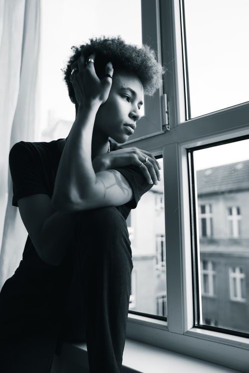 Free Black and white portrait of a young adult woman seated by a window in Berlin. Stock Photo
