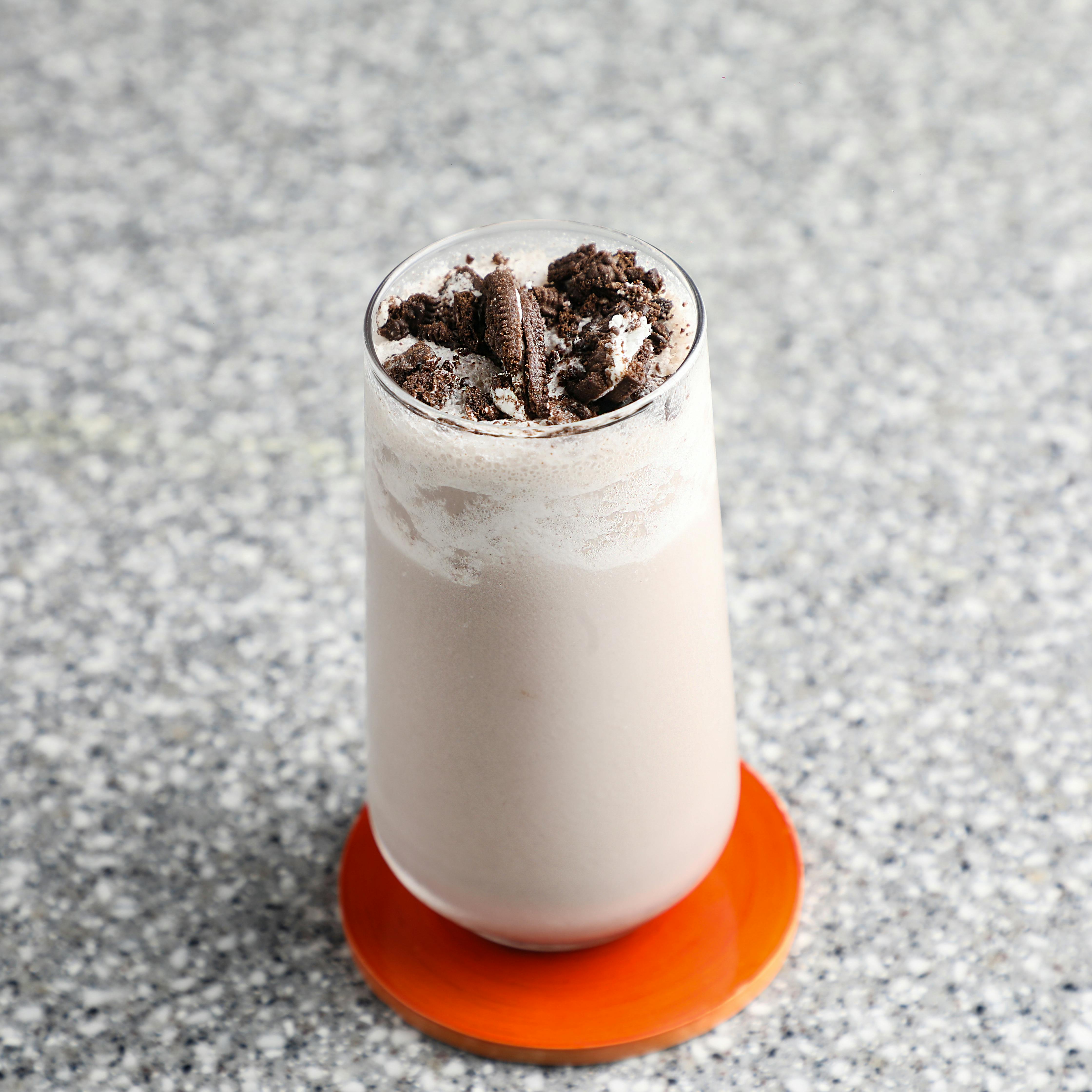 Anil  Sharma - A creamy cookies and cream milkshake topped with chocolate cookies on a textured table surface.