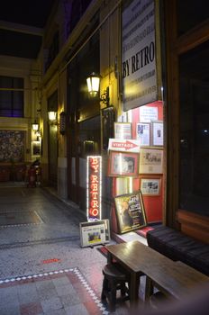 Explore a nostalgic storefront display in a dimly lit alley featuring vintage items and neon signs at night.