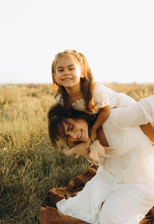 Free Joyful mother and daughter bonding in a sunny outdoor meadow, embracing family love Stock Photo