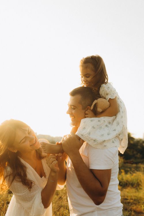 Free Joyful family enjoying a day outdoors, embracing happiness and togetherness under the warm sunlight. Stock Photo