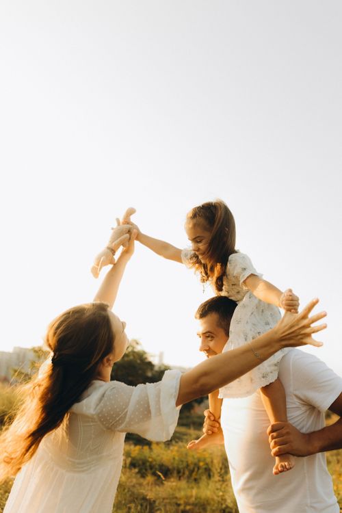 Free A happy family enjoying a moment outdoors in a sunlit field, showcasing love and joy. Stock Photo