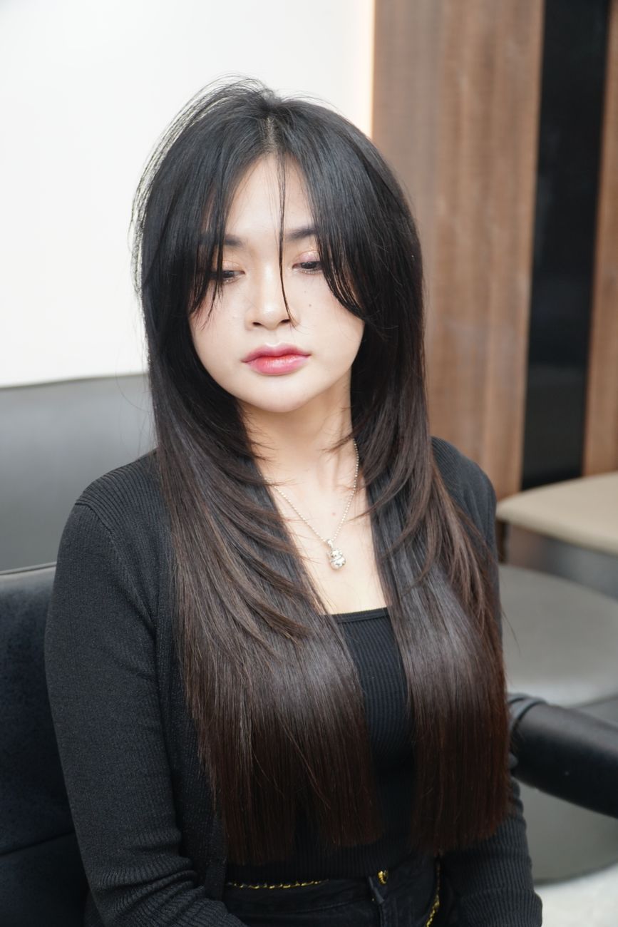 Portrait of a young woman with long straight hair sitting in a salon chair.
