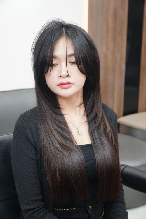 Free Portrait of a young woman with long straight hair sitting in a salon chair. Stock Photo