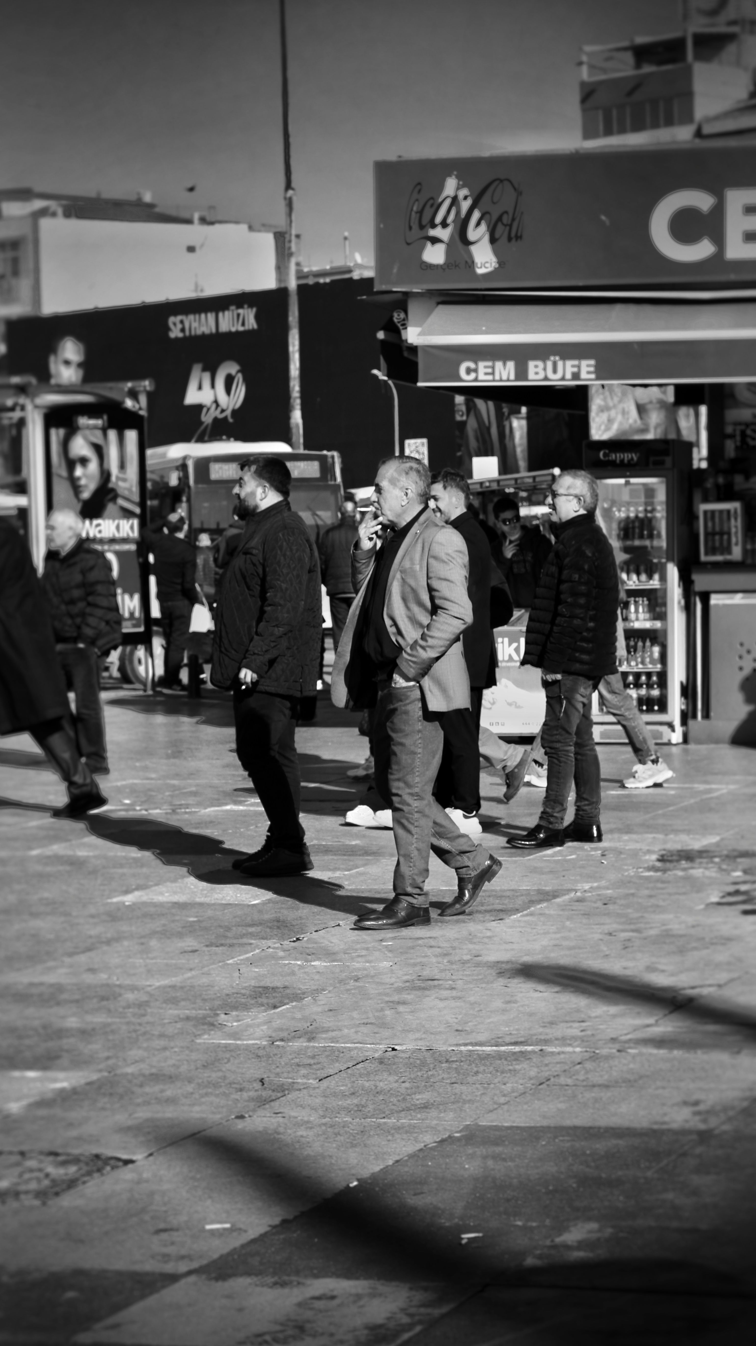 Black and white photo of people at a street kiosk in an urban area.