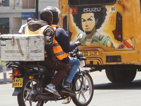 Motorcycle delivery service in Nairobi with vibrant street art in the background.