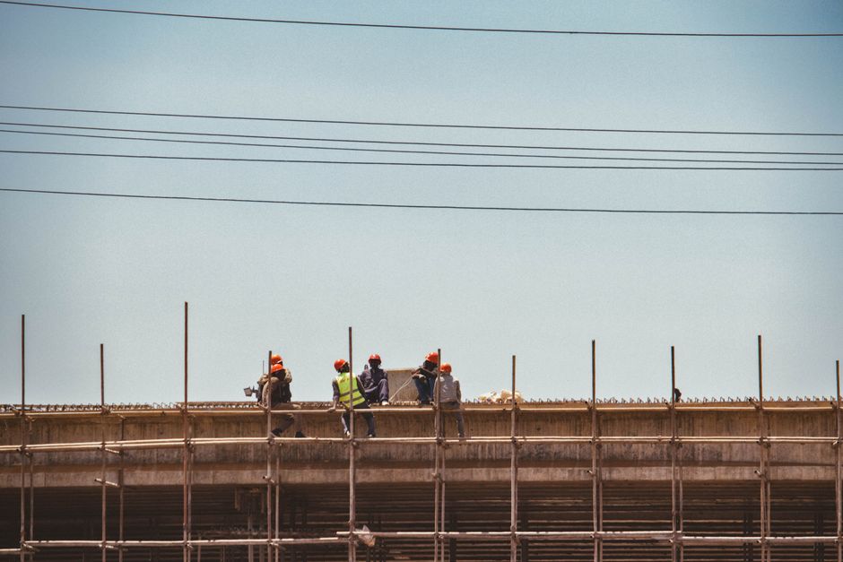 Construction workers on scaffold against a clear sky in Nairobi, Kenya.
