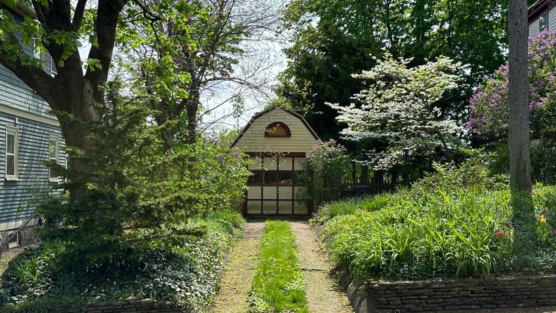 A garden path leading to a small building at the bottom of the garden