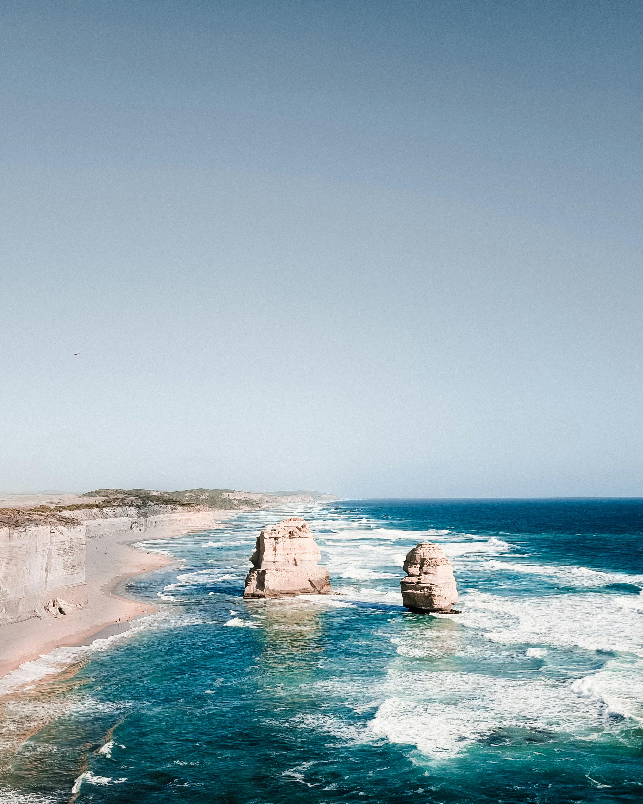Breathtaking aerial shot of the Twelve Apostles rock formations along Australia's Great Ocean Road under a clear blue sky.