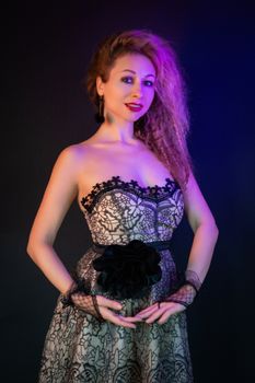 Elegant woman in a lace dress posing gracefully against a dark background with vintage styling.