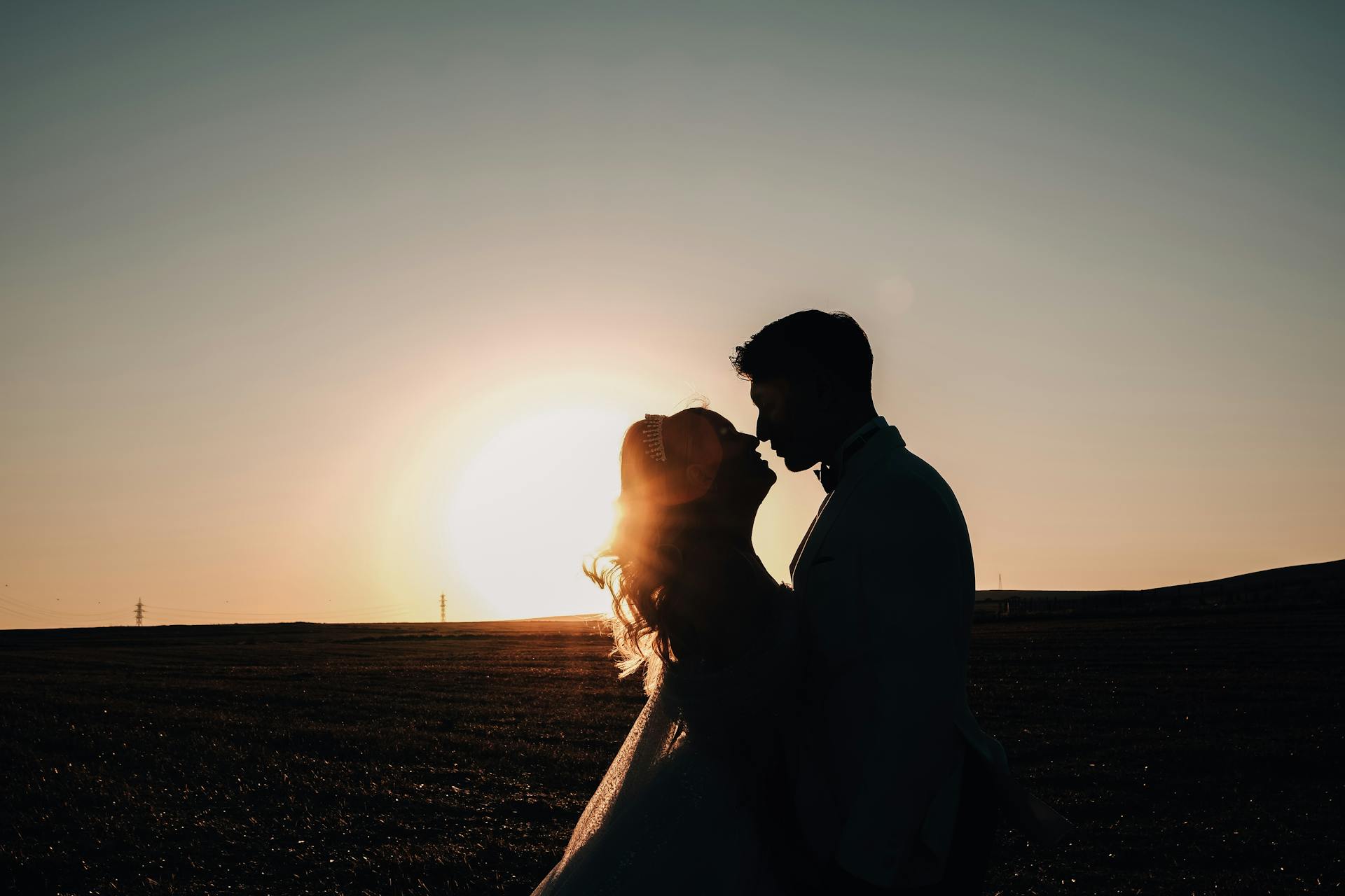 Silhouette of a couple embracing at sunset, perfect for a romantic wedding theme.