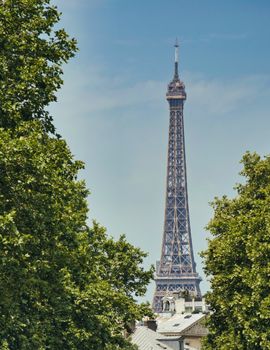 The Eiffel Tower stands tall in Paris, framed by vibrant trees under a clear blue sky.