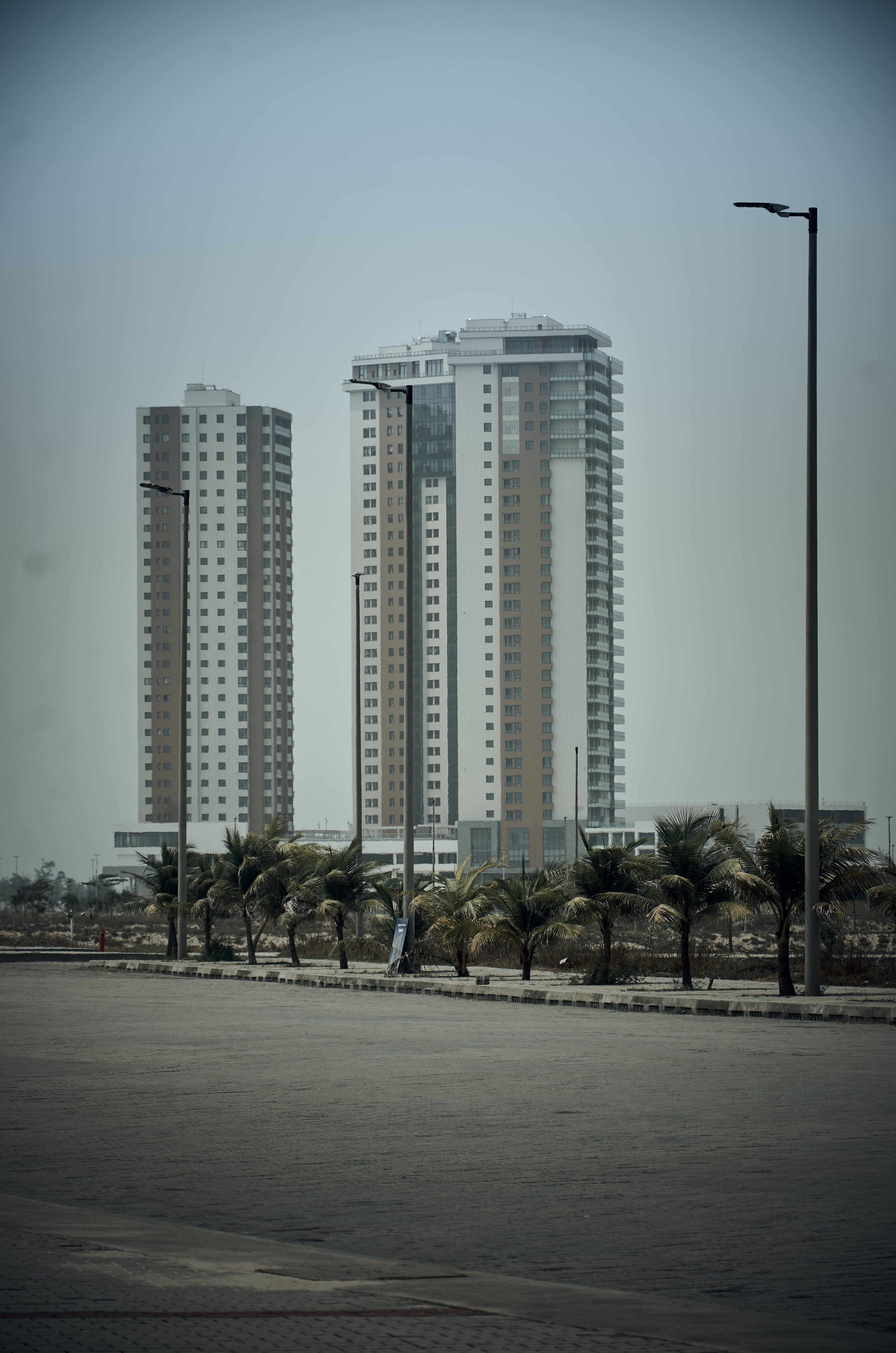 Tall residential towers with palm-lined streets under a cloudy urban skyline.
