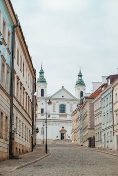 A picturesque view of a historic church on a cobblestone street in Warsaw, Poland.