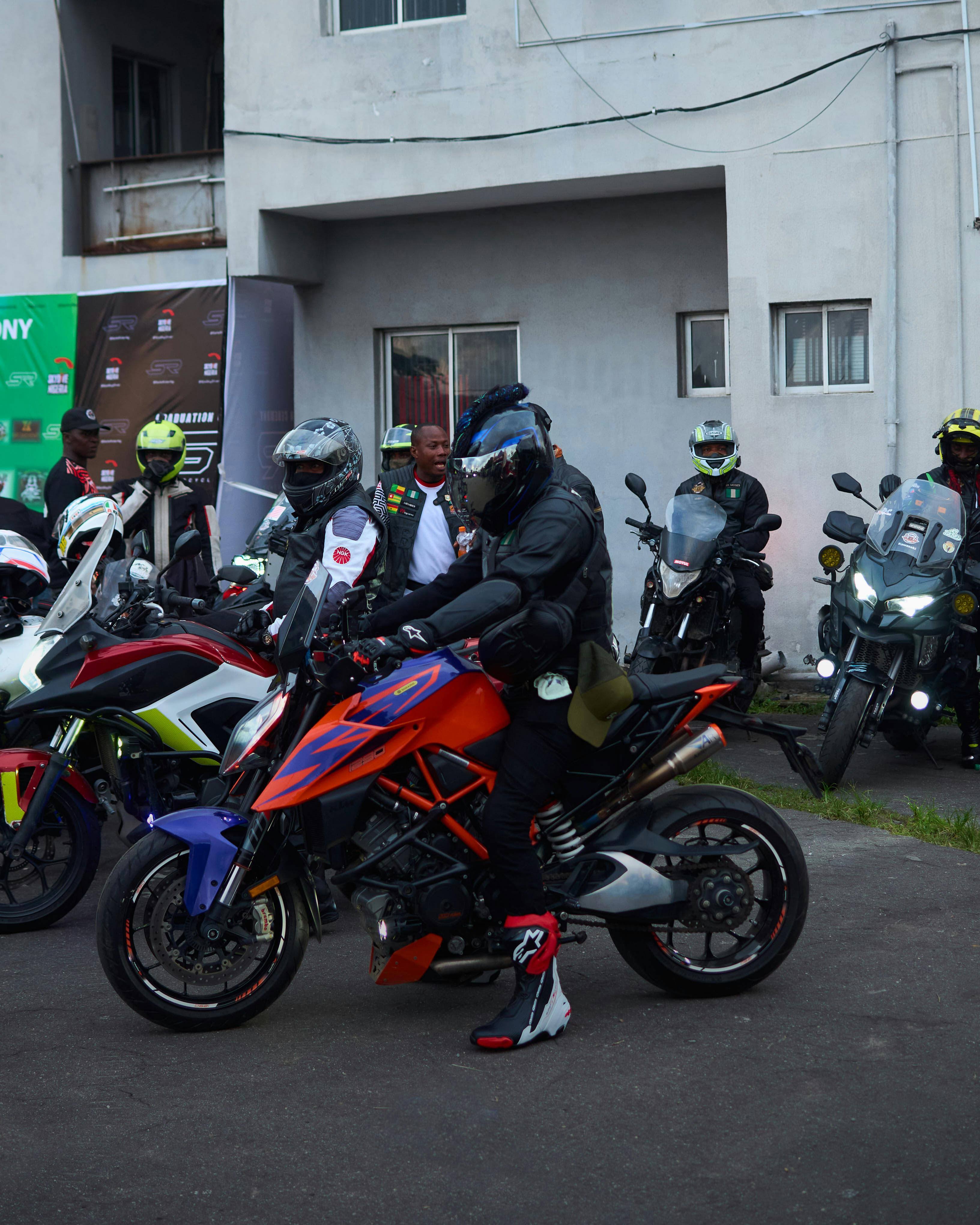 Motorcyclists in gear gather with their sports bikes in an urban setting, ready to ride.
