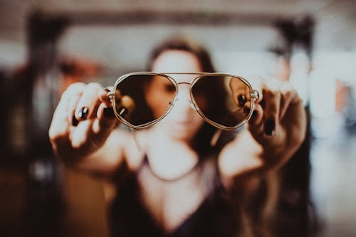 Shallow Focus Photo of Person's Hand Holding Sunglasses