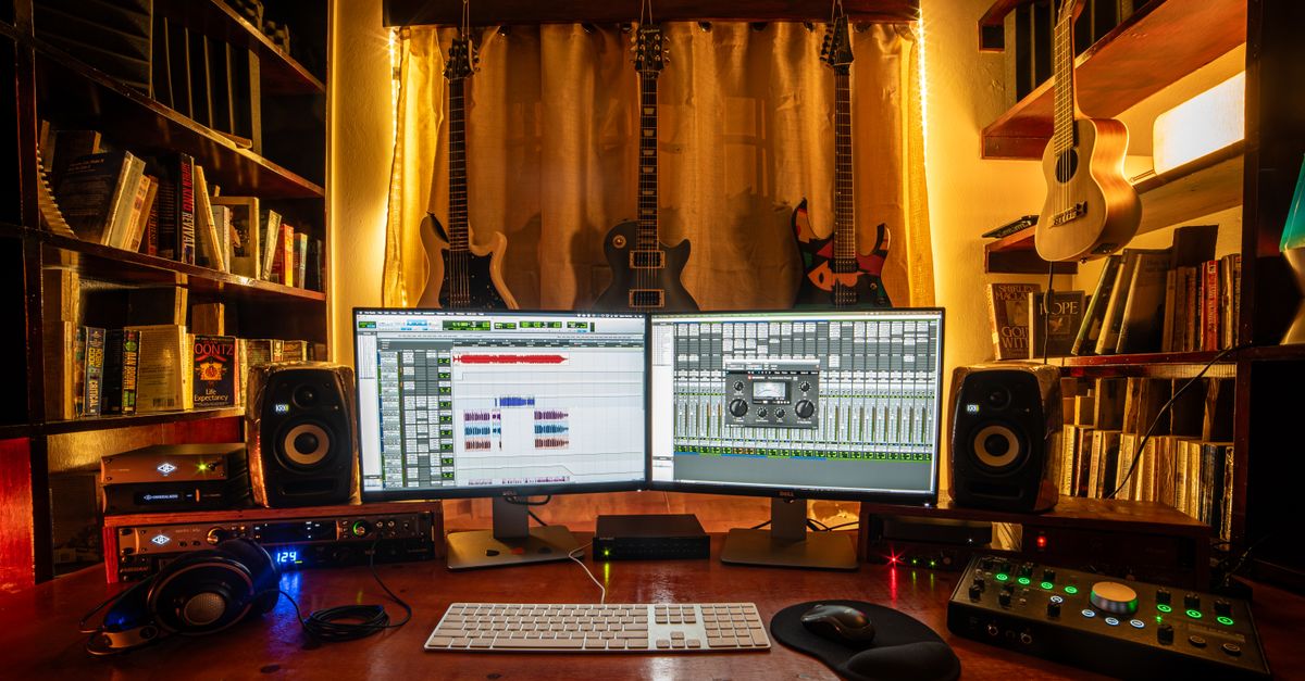 A bedroom recording setup with a laptop showing an AI music app, headphones, and a guitar