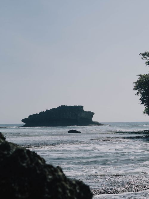 Free Serene ocean view with a rocky island and gentle waves, creating a tranquil atmosphere. Stock Photo