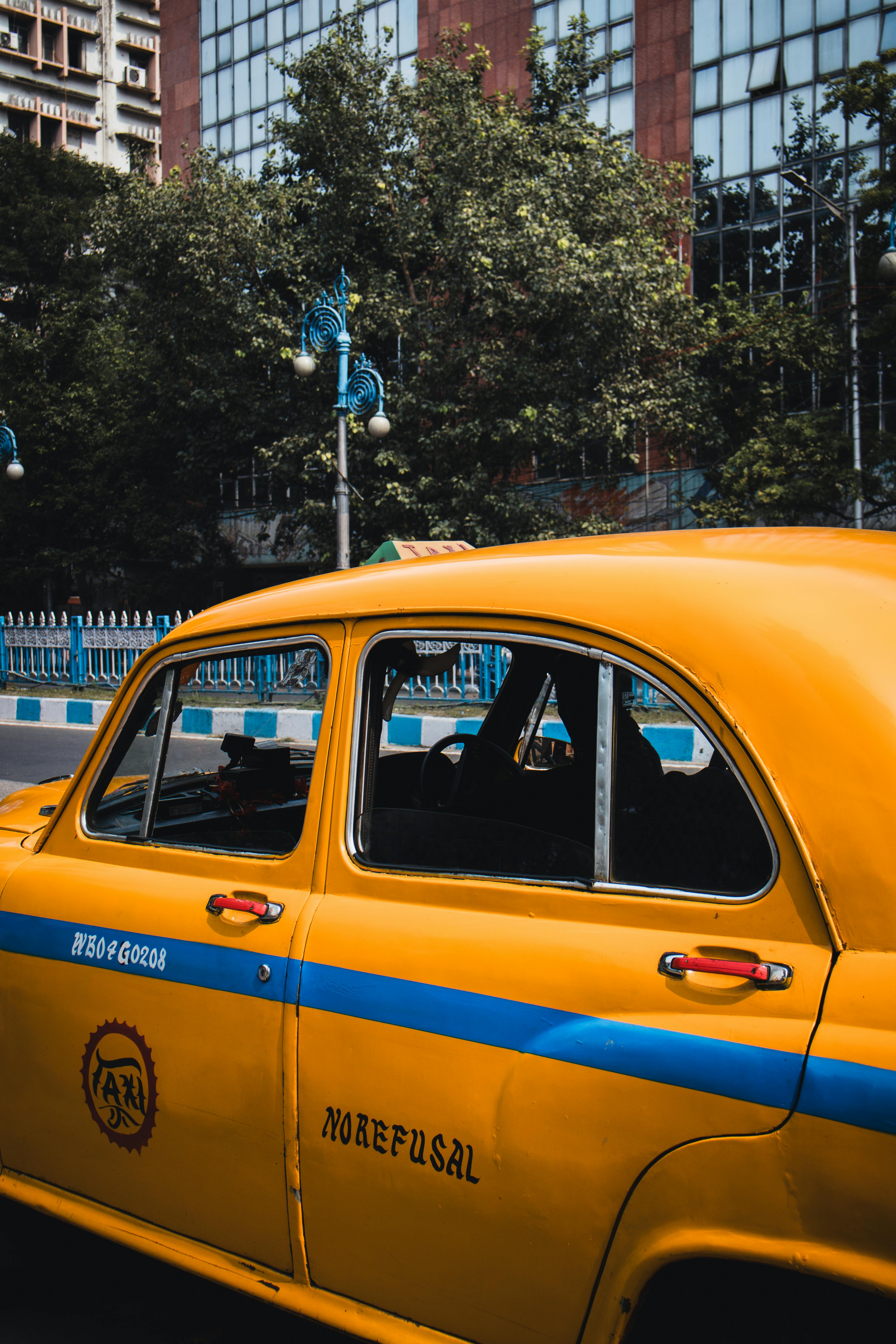 Vibrant yellow taxi in a bustling Kolkata street scene, capturing urban life.