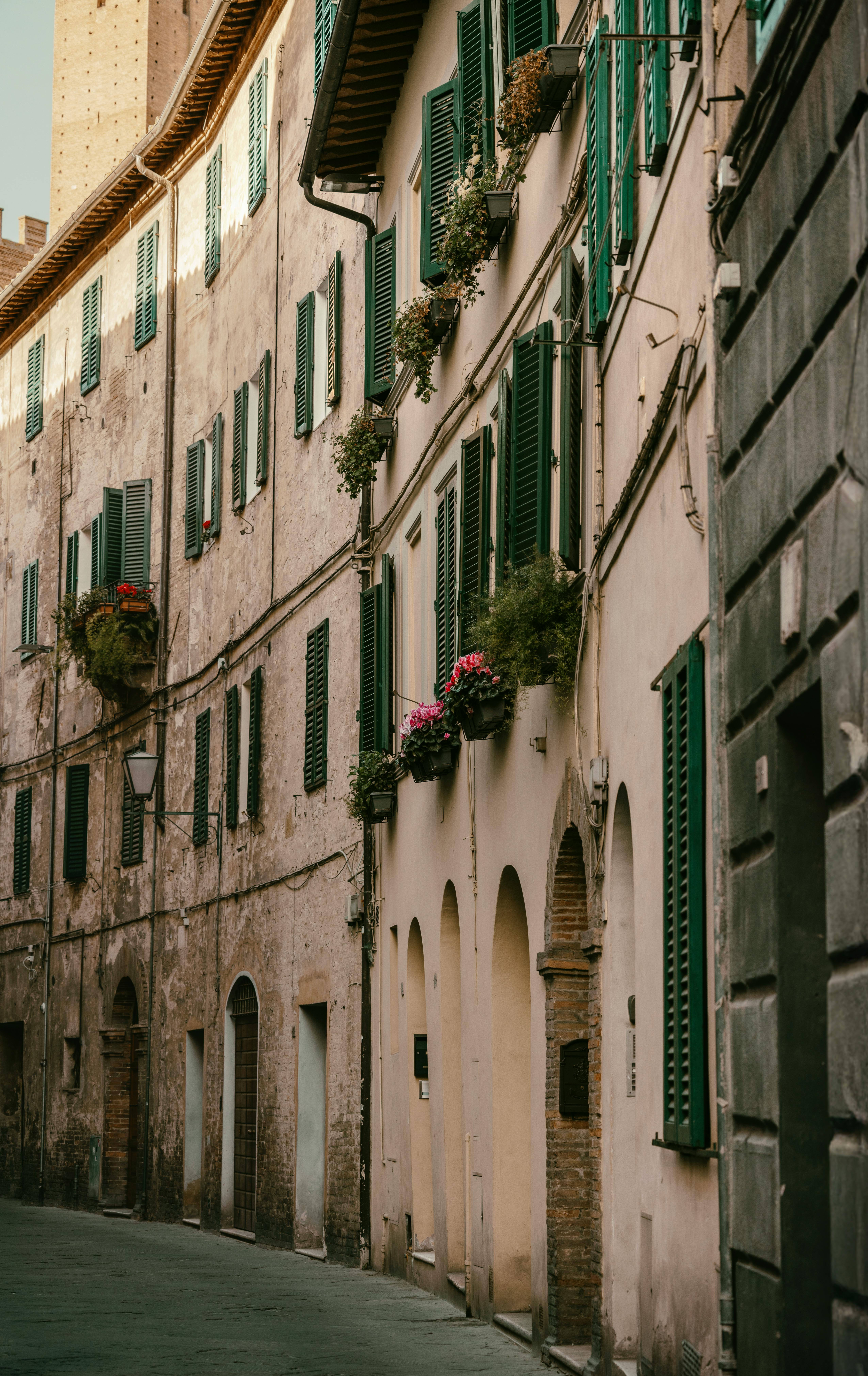 A quaint street in Siena, Spain, showcasing historic architecture with green shutters.