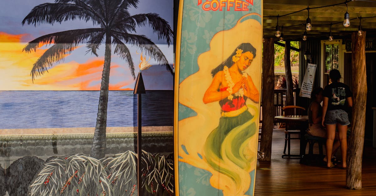 Photo by Tim & Martin Klement Colorful surfboard with Kauai Coffee branding at a Hawaiian café with a mural backdrop.