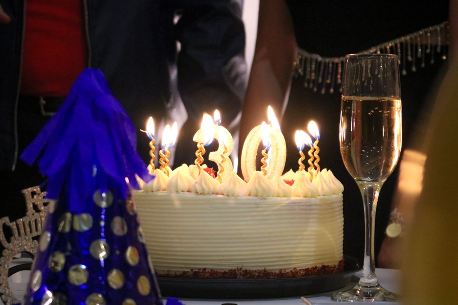 30th birthday cake with candles and champagne for a festive celebration.
