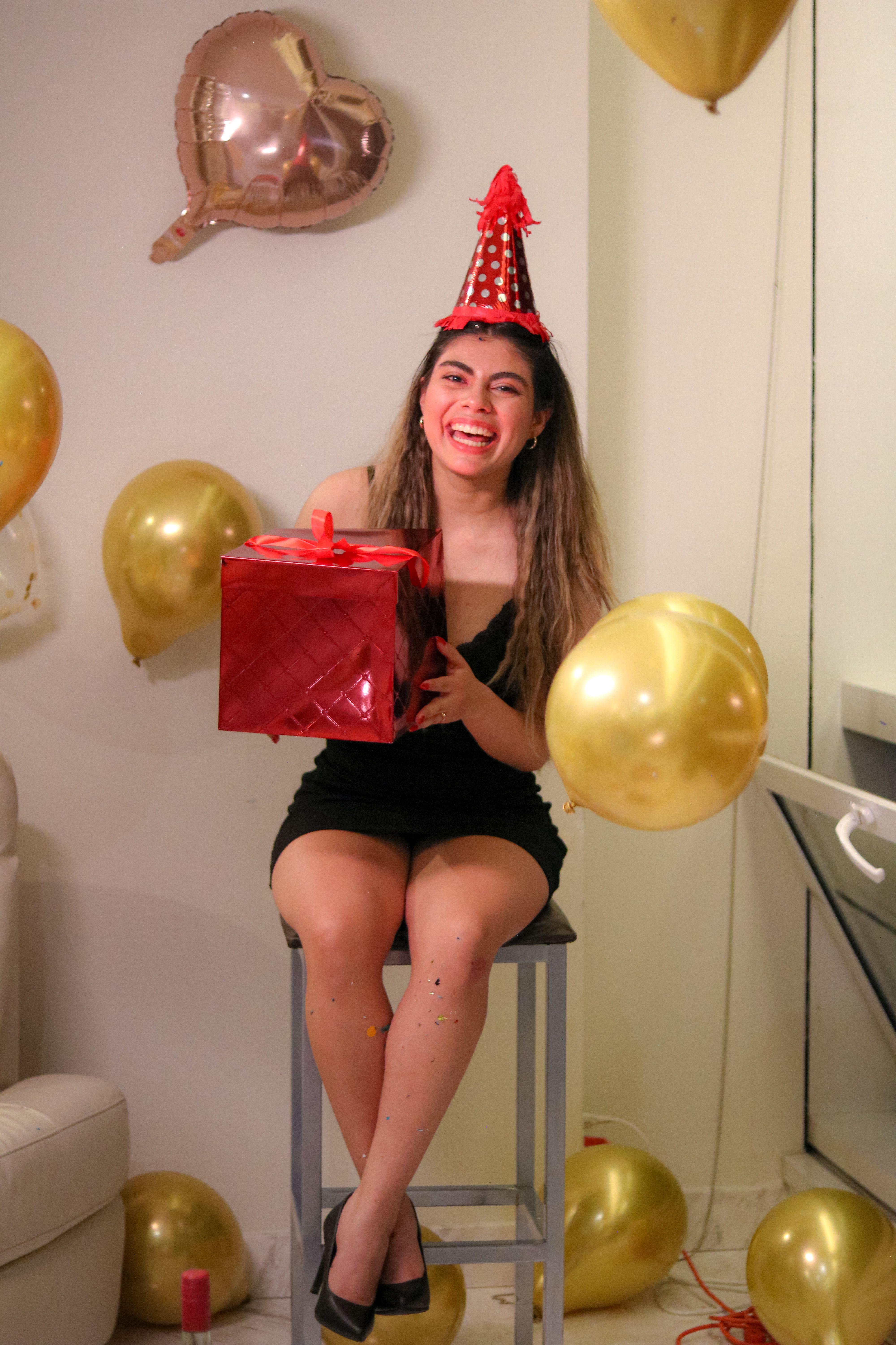 De franc Una dona que porta un barret de festa sosté alegrement un regal durant una celebració d'aniversari festiva. Foto d'estoc
