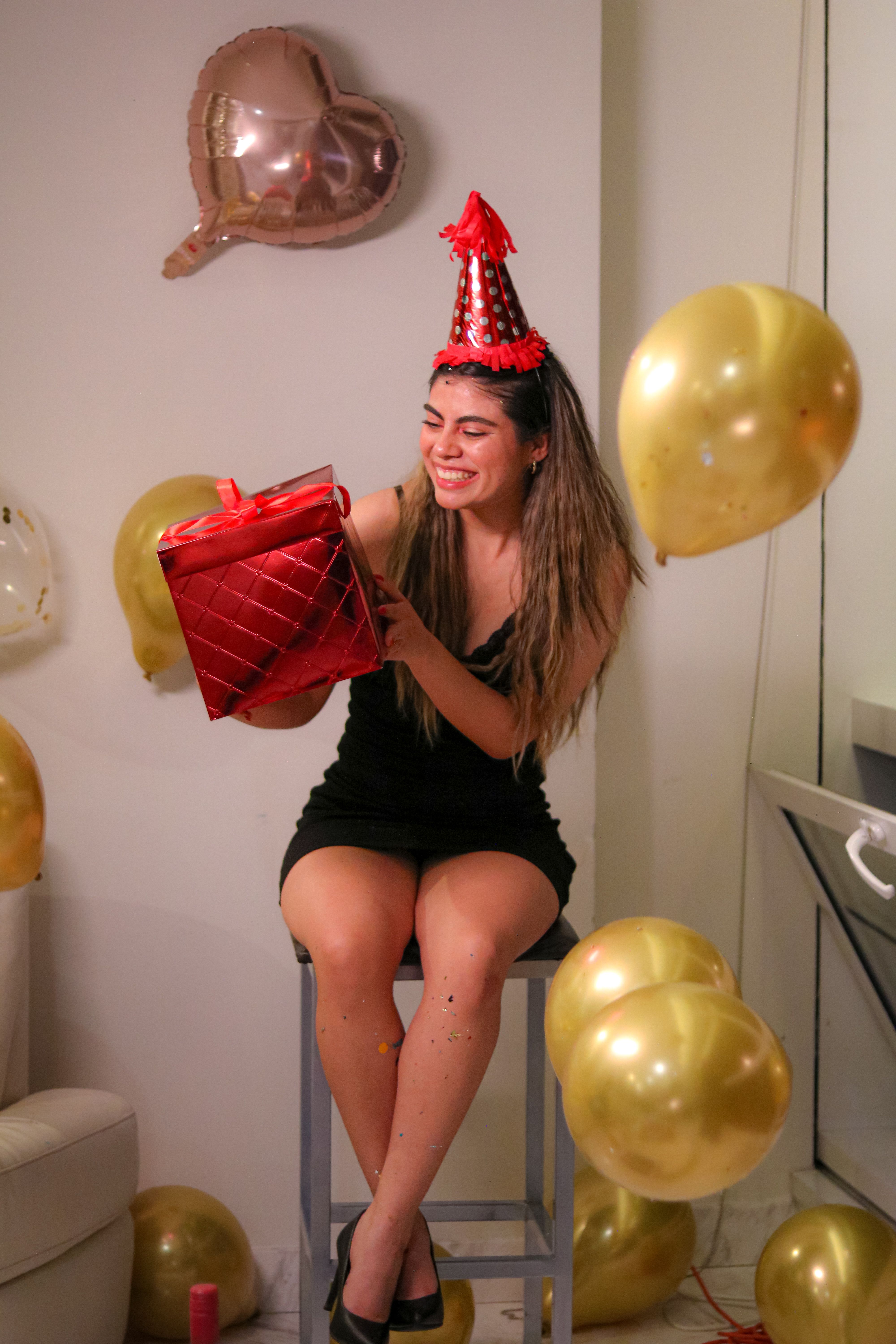 De franc Una dona somrient celebra l'aniversari amb barret de festa, globus i regals a l'interior. Foto d'estoc