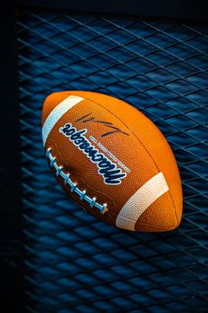 Vibrant photo of an American football resting on a textured metal surface.