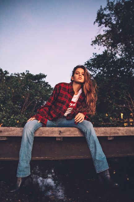 Young woman in casual wear poses outdoors in Rio de Janeiro at dusk.