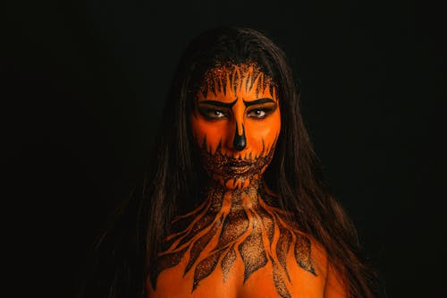 Woman With Face and Body Paint Against Black Background