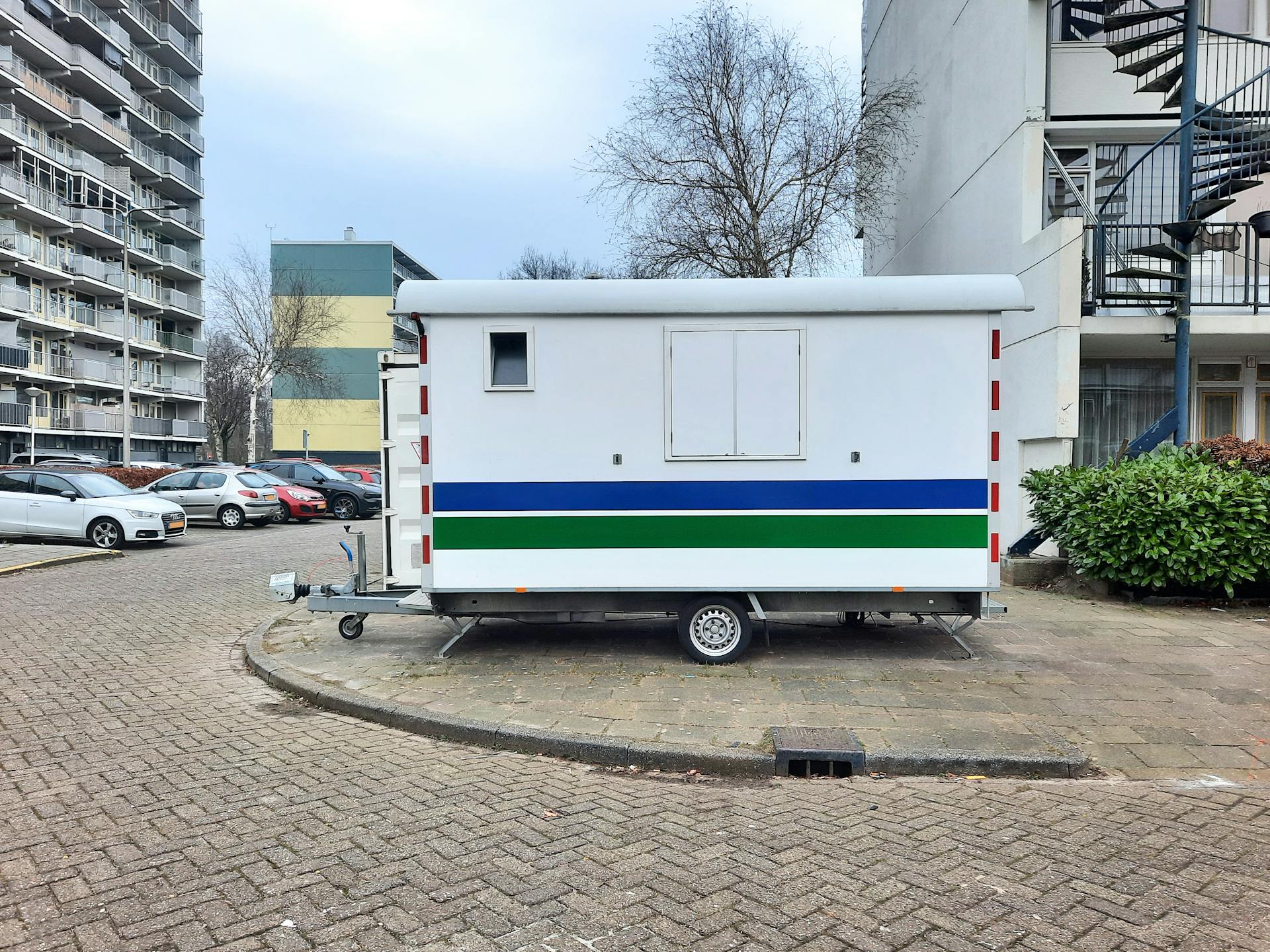 A white mobile trailer parked in an apartment complex parking lot.