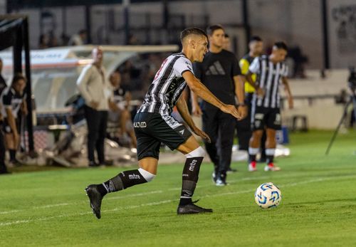 Free Soccer player dribbling ball during a match on a well-lit stadium field. Stock Photo