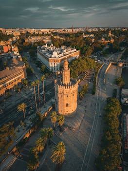 Stunning drone perspective of Torre del Oro surrounded by the vibrant cityscape of Seville, Spain.