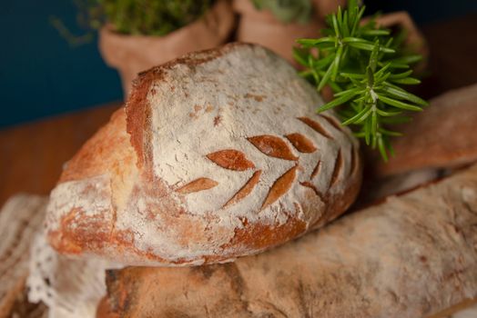 Close-up of artisan bread with a leaf design, accompanied by fresh rosemary sprigs.