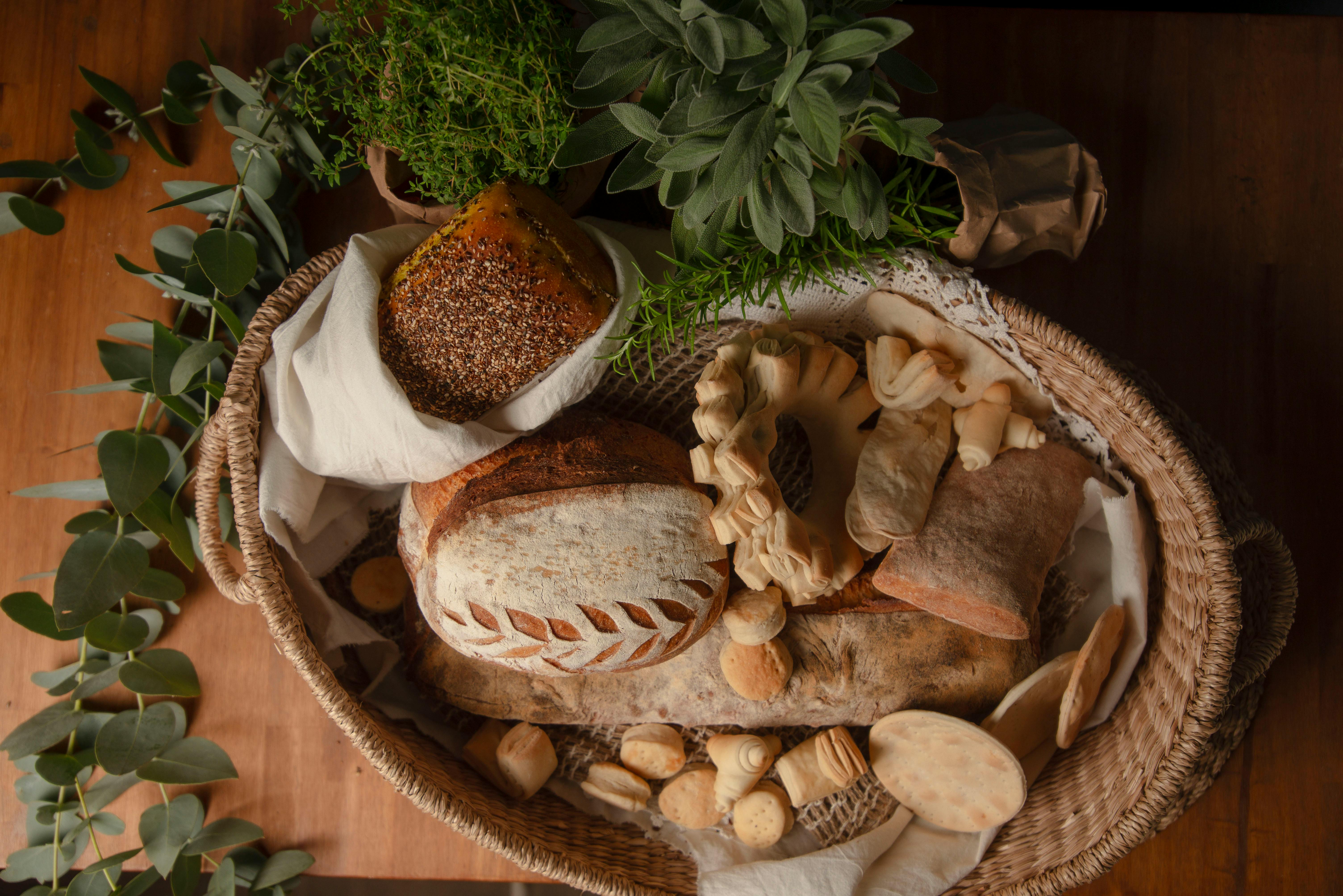 A wicker basket filled with various breads and fresh herbs, creating a rustic look.