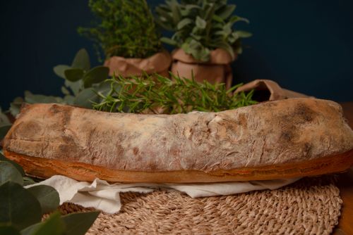 Free Golden rustic bread loaf with fresh herbs on a woven mat, exuding warmth and homeliness. Stock Photo