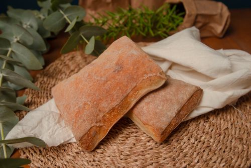 Free Close-up of fresh rustic artisan bread on woven mat with greenery. Stock Photo