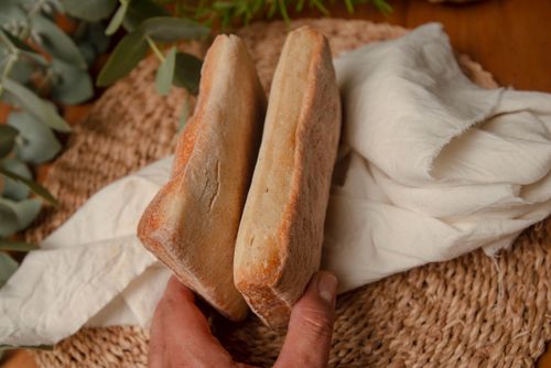 Free Close up of hands holding ciabatta bread on a rustic table setup with greenery. Stock Photo