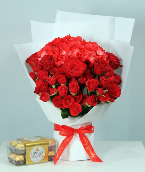Free Luxurious bouquet of red roses with a Ferrero Rocher chocolate box, perfect for special occasions. Stock Photo