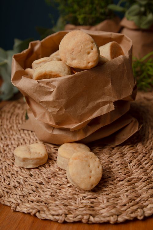 Free Freshly baked biscuits in a rustic brown paper bag on a woven mat, a perfect snack choice. Stock Photo