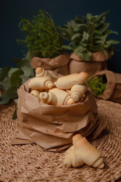 Free Close-up of freshly baked rolls in a paper bag surrounded by herbs on a woven mat. Stock Photo