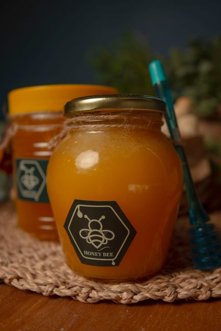 Close-up of a honey jar with hexagonal honeybee label and honey dipper on a wooden surface. - Top Brands and Expert Tips for Choosing Natural Sweeteners
