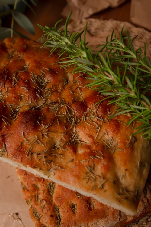 Free Close-up of freshly baked rosemary focaccia bread on a wooden surface. Stock Photo