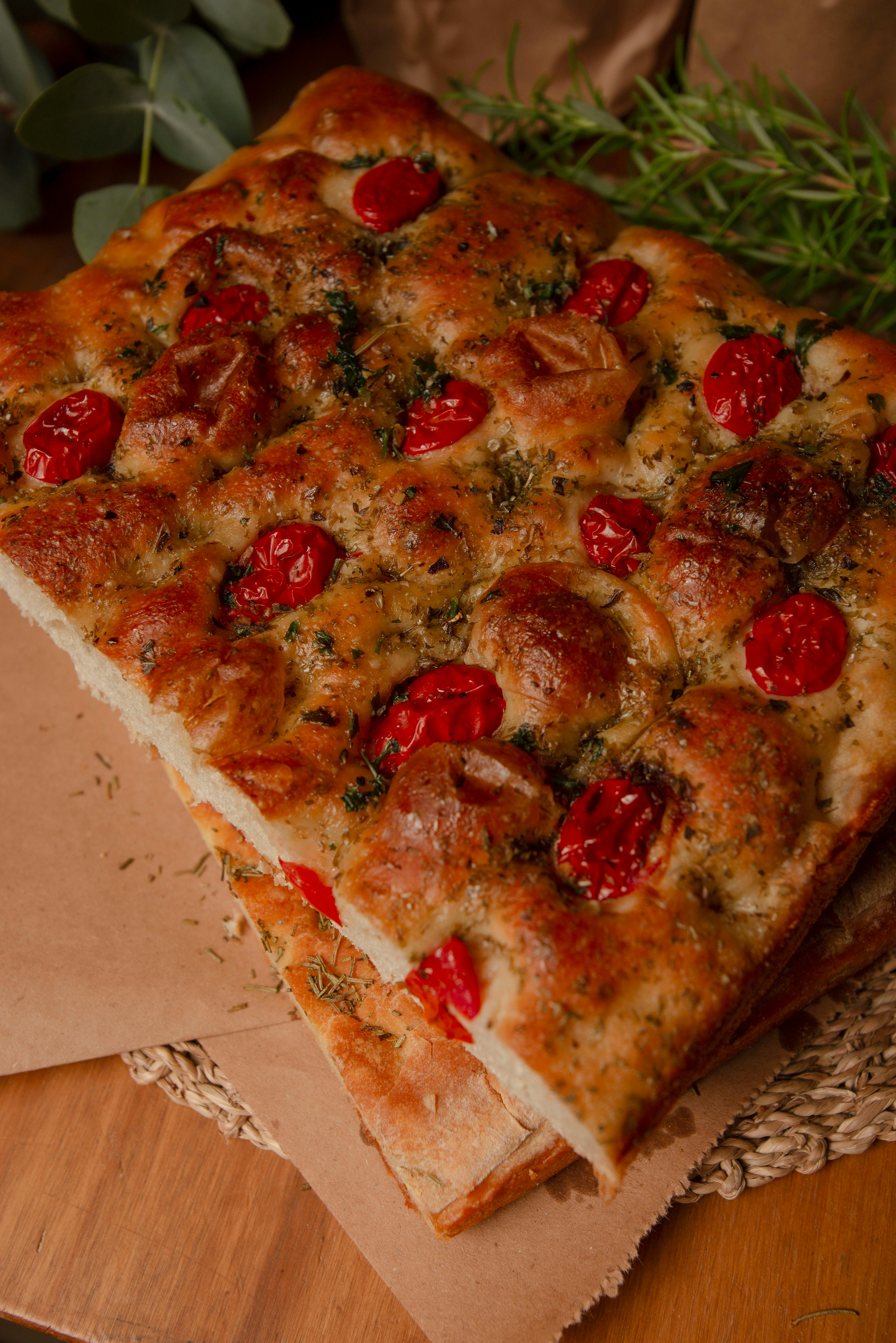 Natalia Olivera - Freshly baked focaccia topped with cherry tomatoes and herbs, offering a rustic feel.