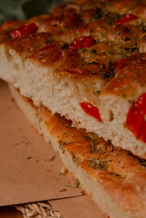 Free Close-up of delicious focaccia bread topped with herbs and cherry tomatoes. Stock Photo
