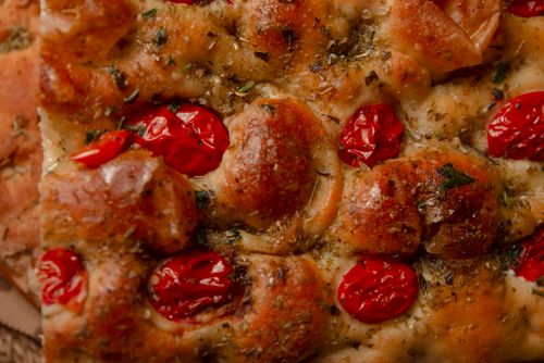 Free Delicious Italian focaccia with cherry tomatoes and herbs. Perfect for food lovers. Stock Photo
