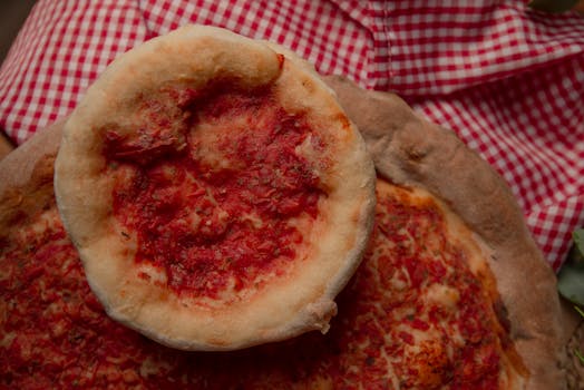 Close-up of rustic homemade pizzas with fresh tomato sauce on a checkered tablecloth.
