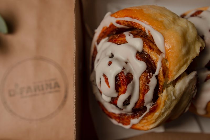Iced cinnamon roll placed on a branded paper bag