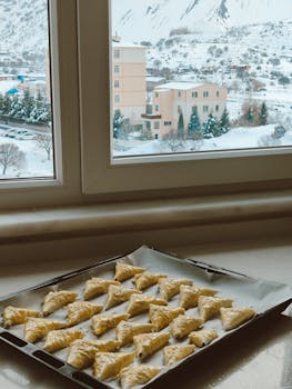 Delicious pastries cooling by a window with a snowy landscape outside.